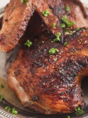 grilled chicken half with char marks on a platter.