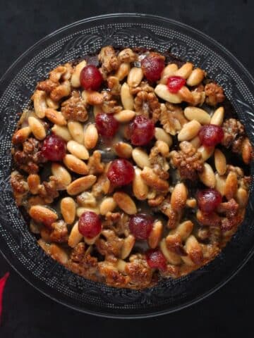 overhead view of mincemeat cake topped with almonds, walnuts and glace cherries.