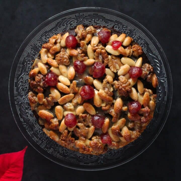 overhead view of mincemeat cake topped with almonds, walnuts and glace cherries.