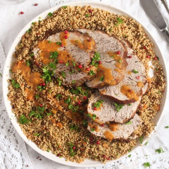 overhead view of a plate with sliced veal roast served on couscous.