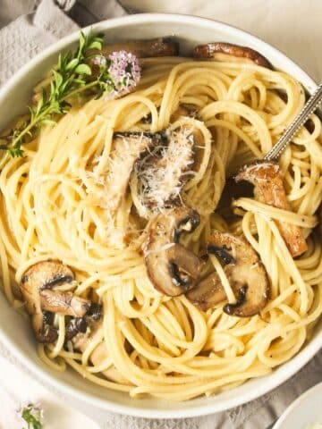 truffle oil pasta with mushrooms in a bowl with a fork in it.