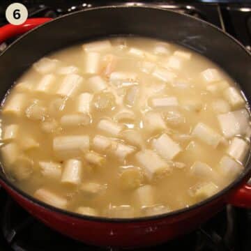 cooking white asparagus pieces in a pot to make soup.