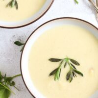 two bowls of soup with asparagus, cream and tyhme.