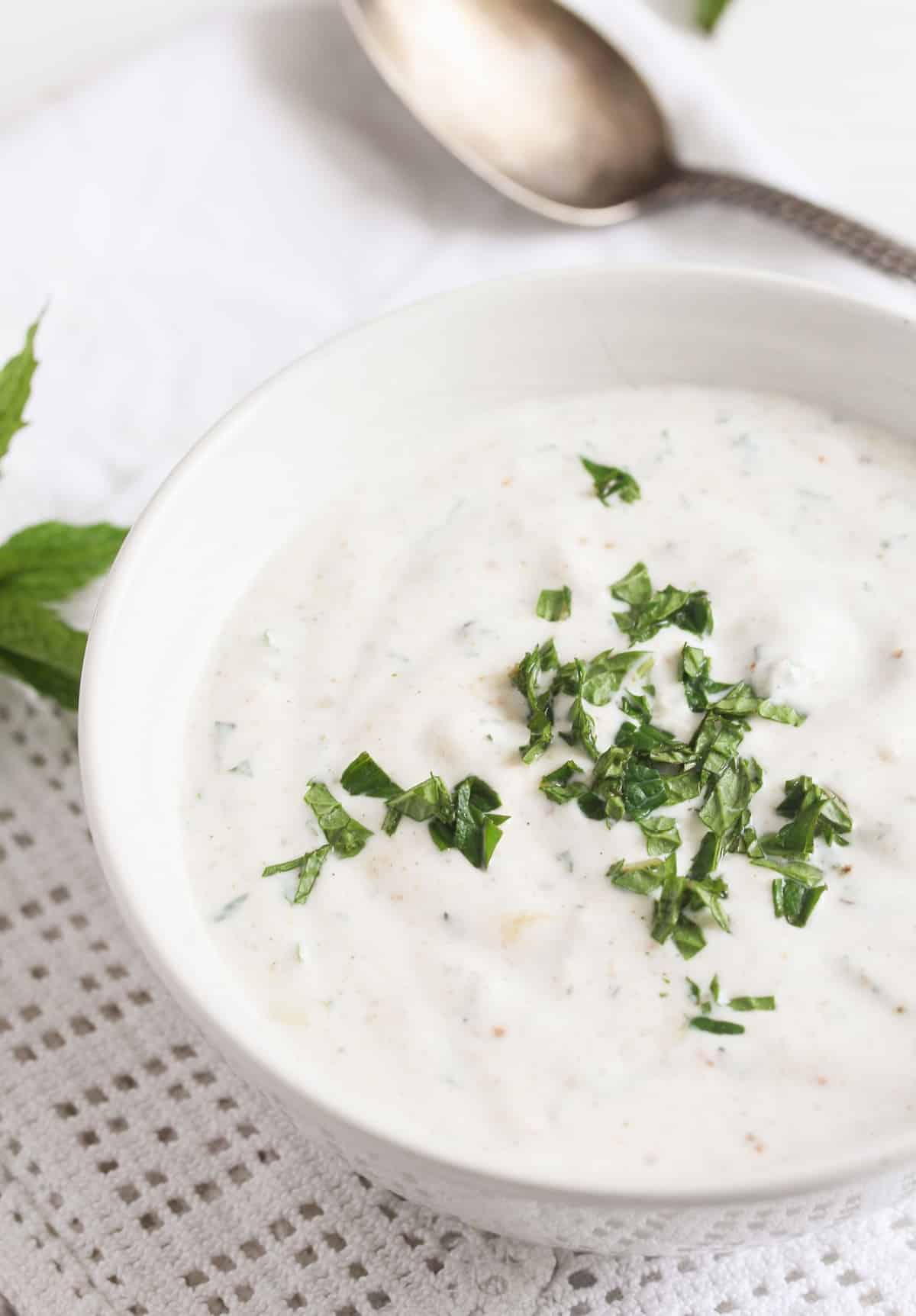 close up bowl with herb sauce with a spoon near it.