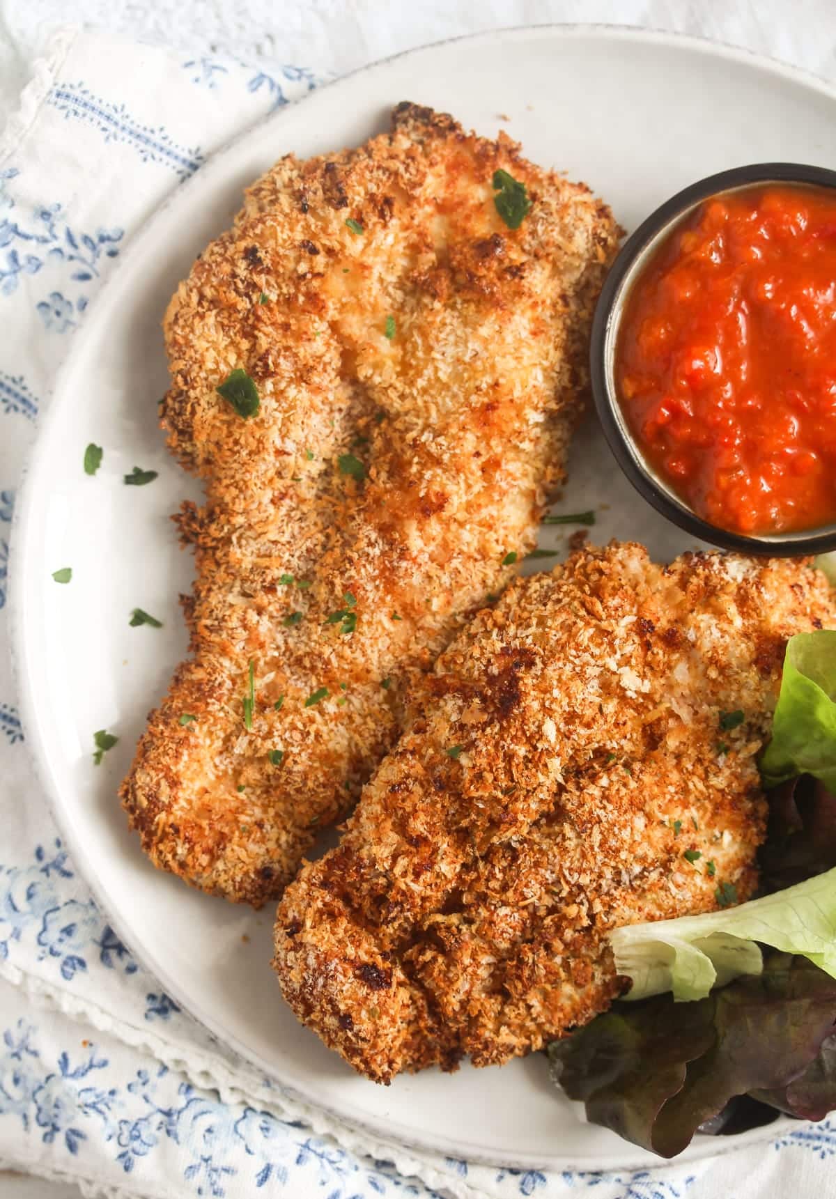crispy panko chicken breast slices with chili dip and salad leaves.