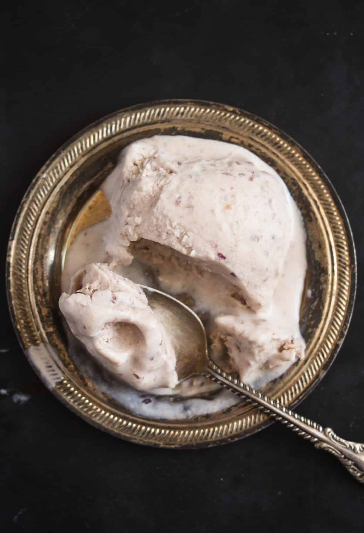 melting ball of cherry amaretto ice cream on a small silver plate.