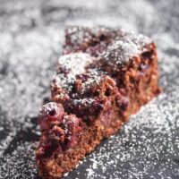 slice of chocolate cake with cherries and icing sugar.