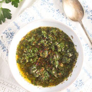 bowl with parsley and mint chimichurri with a spoon beside it.