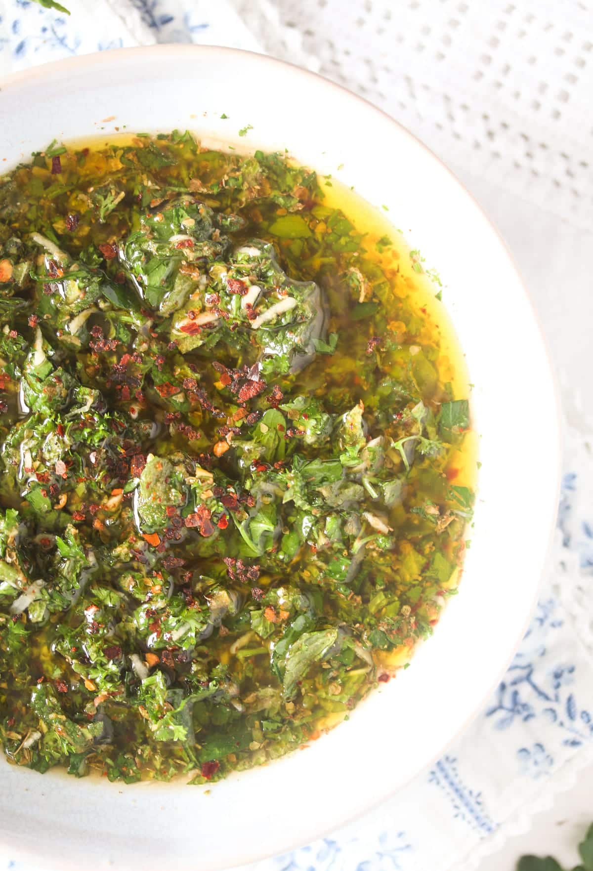 close up bowl of chimichurri sauce made with mint, parsley, chili and garlic.