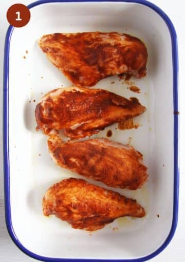 four chicken breasts rubbed with oil and seasoning in a oiled baking dish before baking.