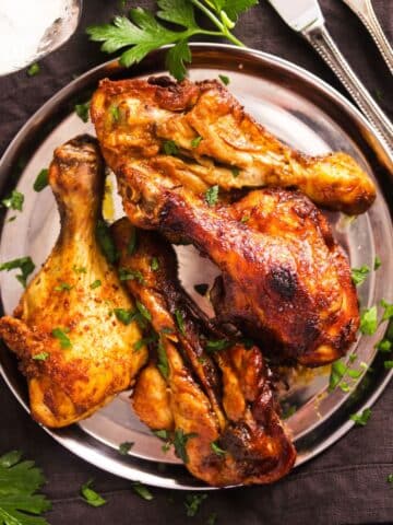 overhead view of butterflied chicken legs on a silver plate.