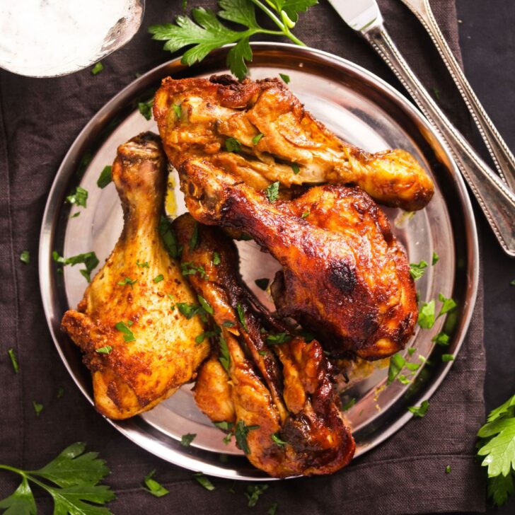 overhead view of butterflied chicken legs on a silver plate.