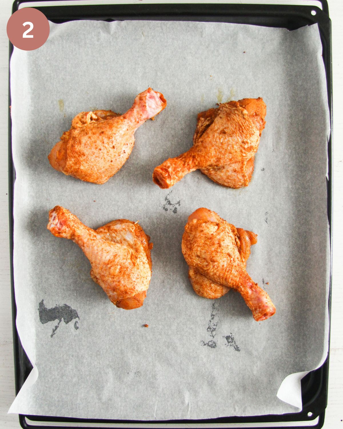for seasoned, raw butterflied chicken legs on a baking sheet lined with white paper.