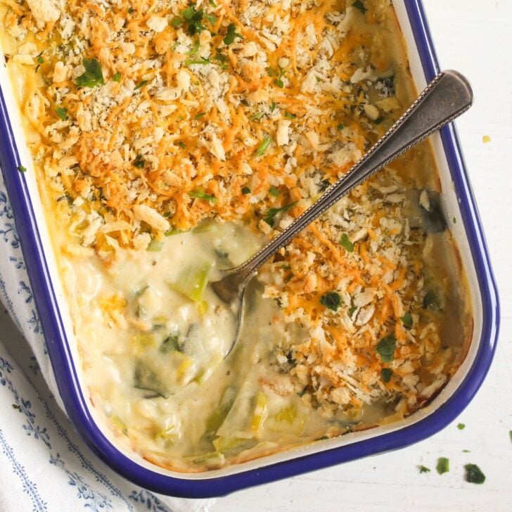 cheesy leeks showing the sauce in a email baking tin with a spoon in it.