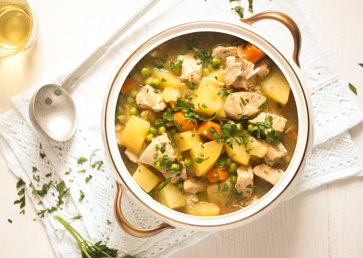 overhead view of chicken and potato stew in a vintage bowl with a spoon beside it.