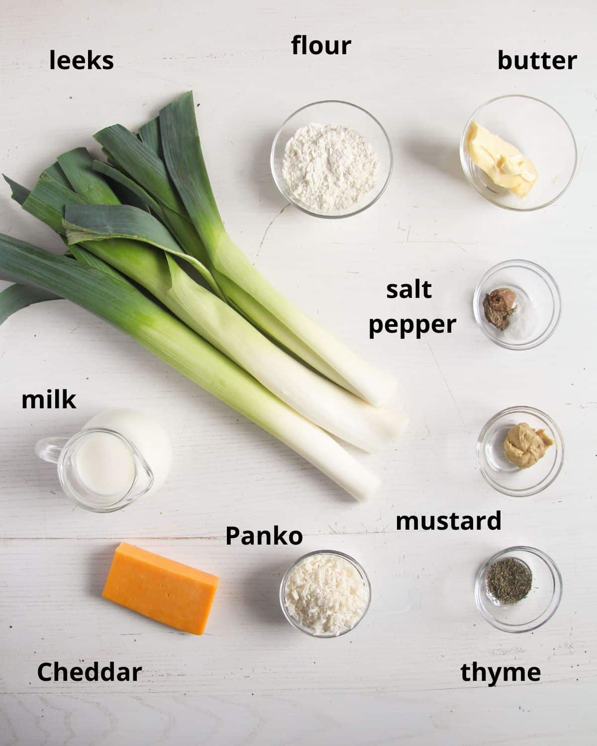 listed ingredients for making leeks in white sauce with cheddar and panko topping.
