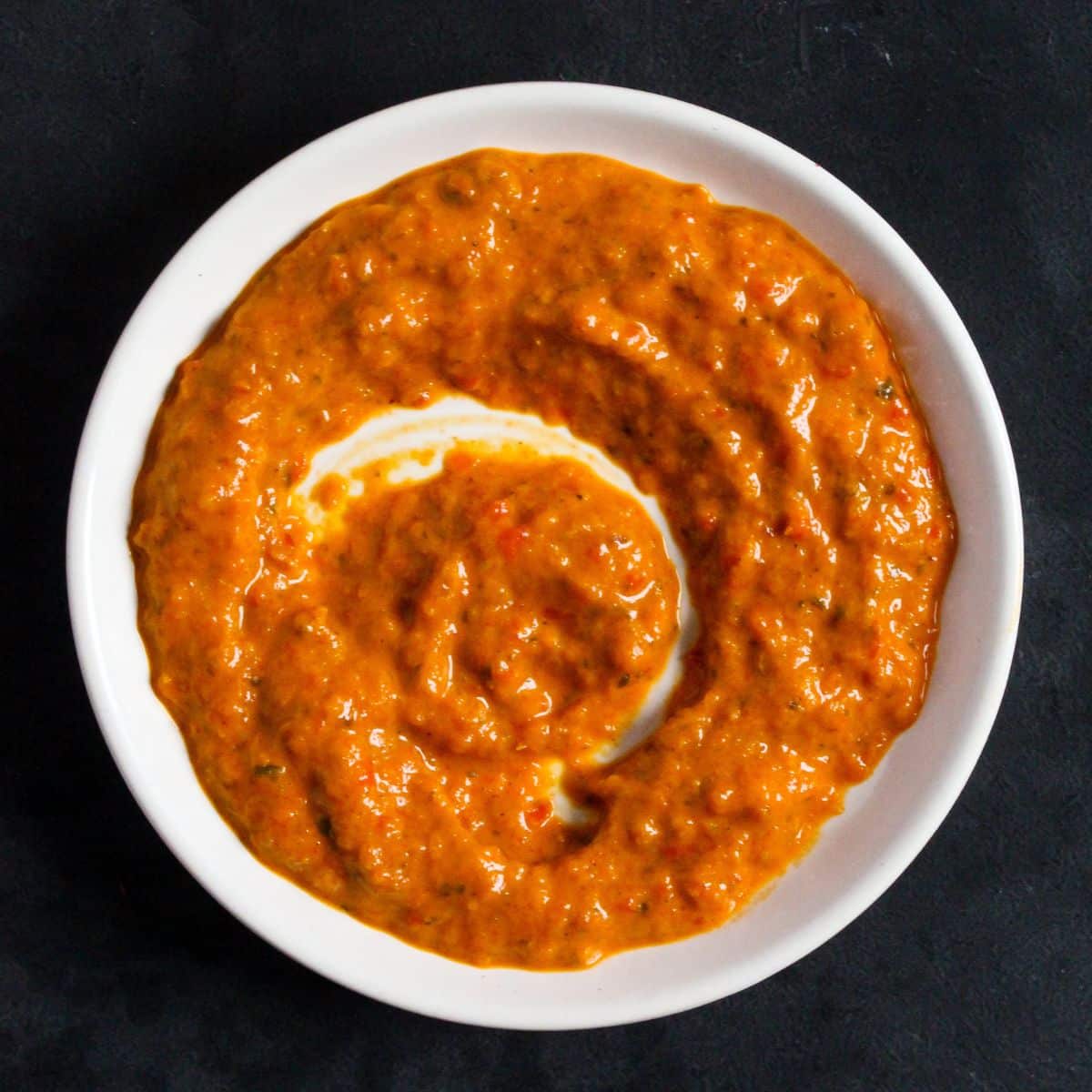 peri peri sauce on a small plate on a black background.