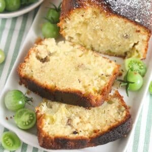 green tomato bread slices on a platter with small tomatoes beside it.