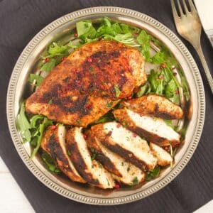 overhead view of pan-fried chicken breasts, one of them sliced.