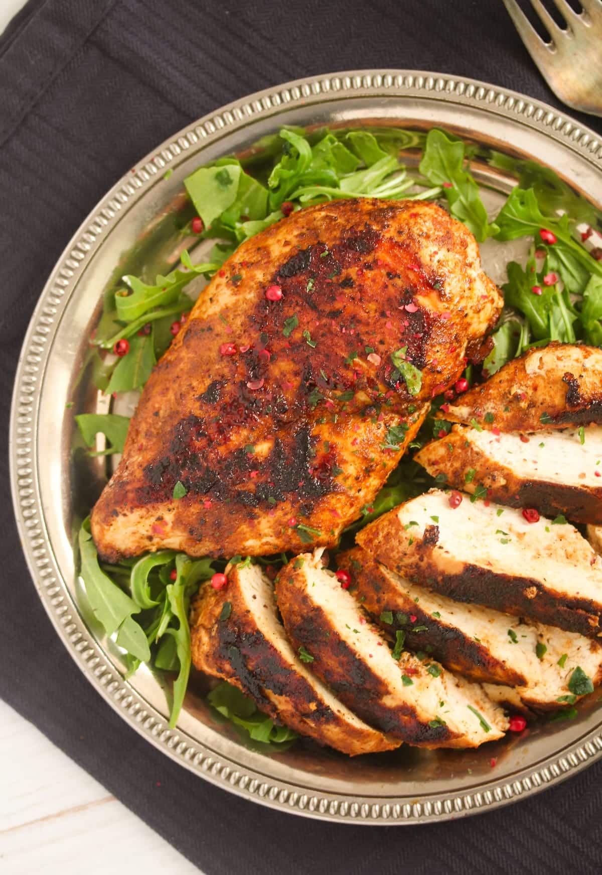 two pan fried chicken breast on a plate with rocket.