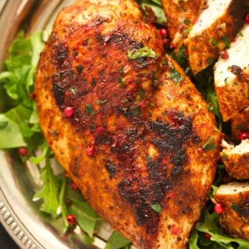 close up golden brown chicken breast on a bed of rocket.