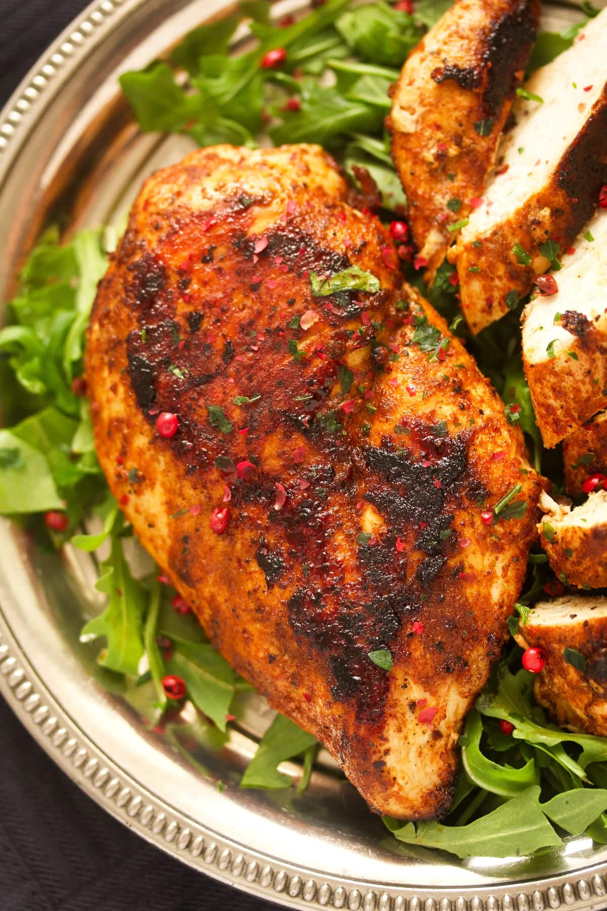 close up golden brown chicken breast on a bed of rocket.