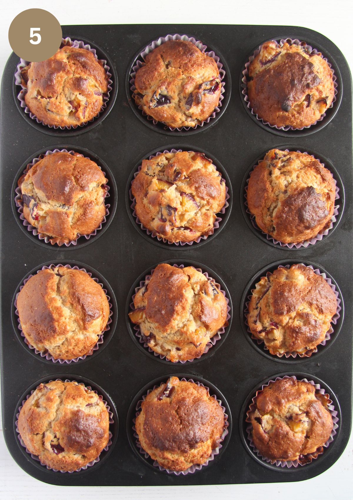12 golden brown muffins in a baking tray.