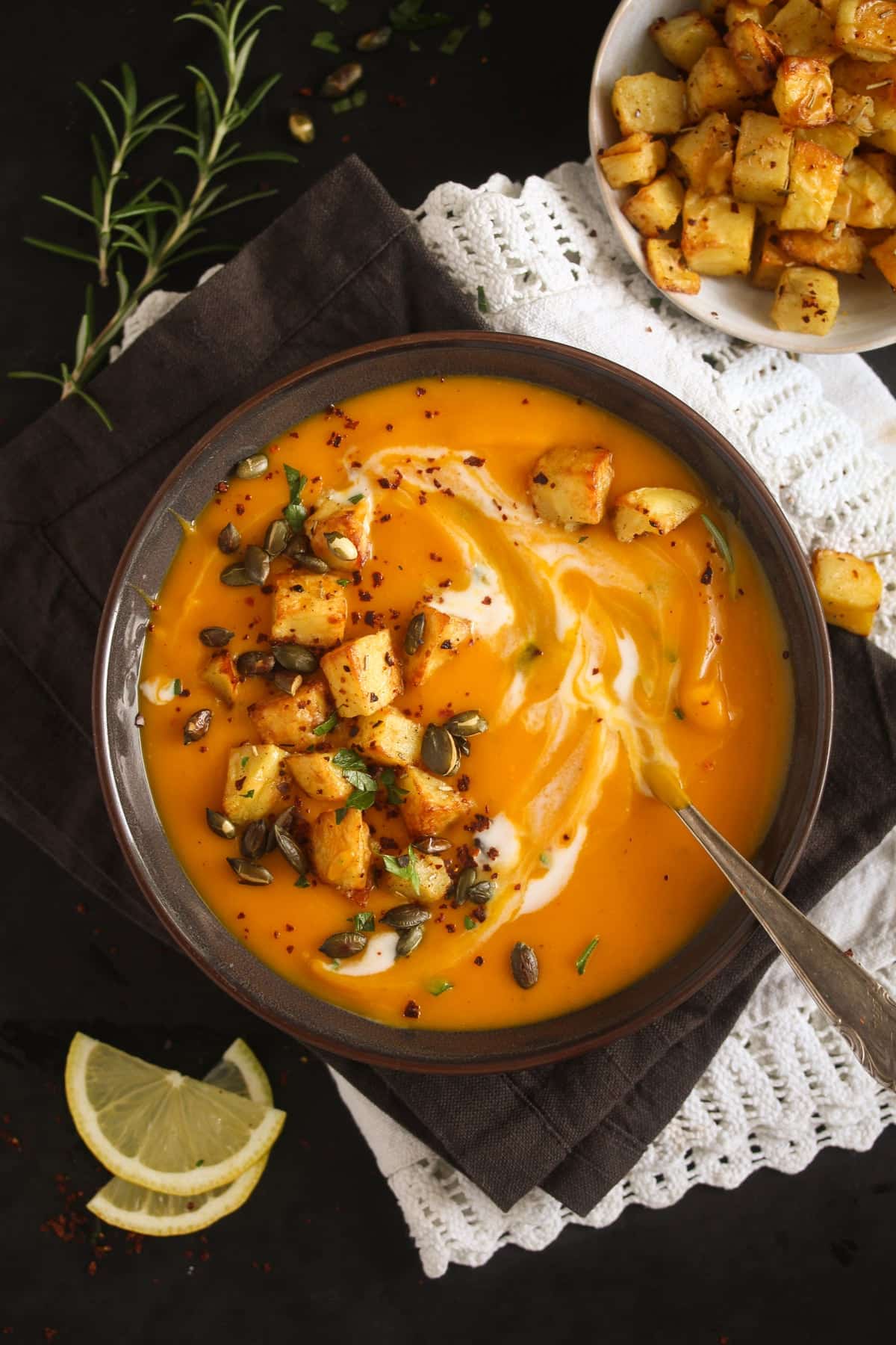 overhead view of a bowl of creamy soup with pumpkin and potato croutons on top.