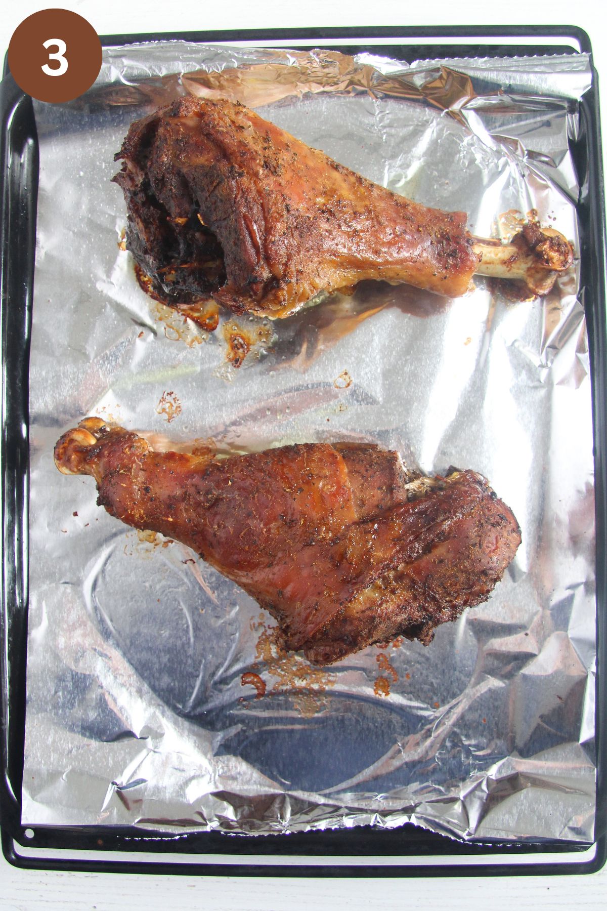 two turkey legs on a baking sheet lined with foil.