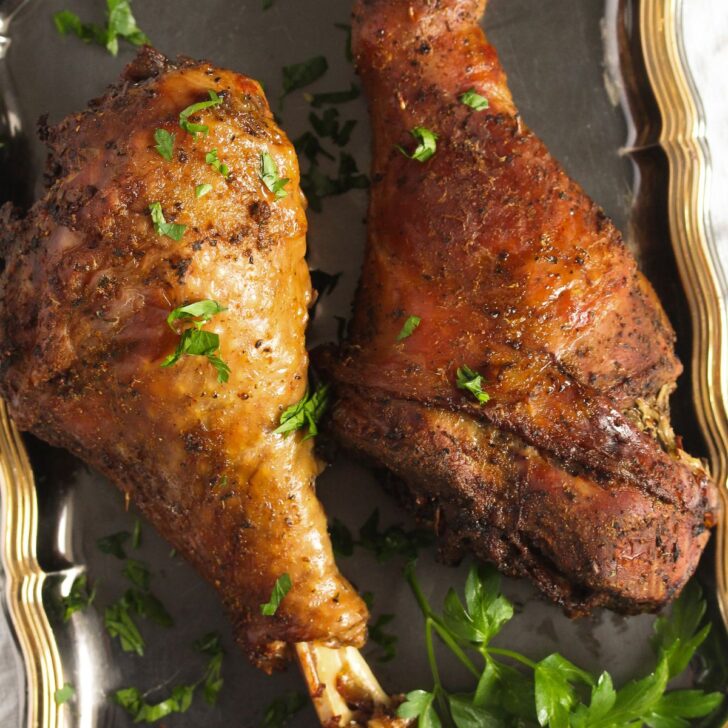close up slow cooker turkey legs sprinkled with parsley.