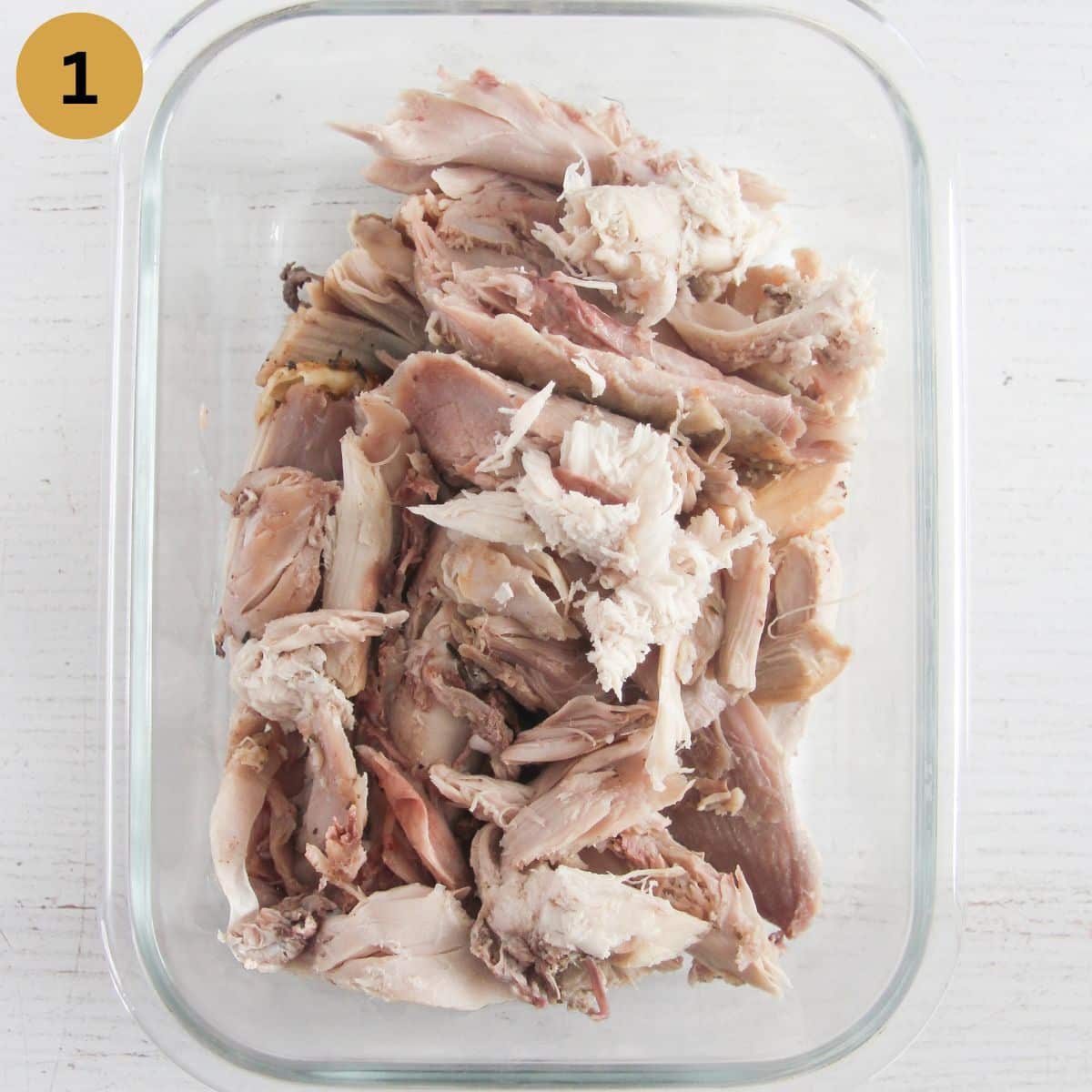 glass container holding cooked and shredded turkey meat.
