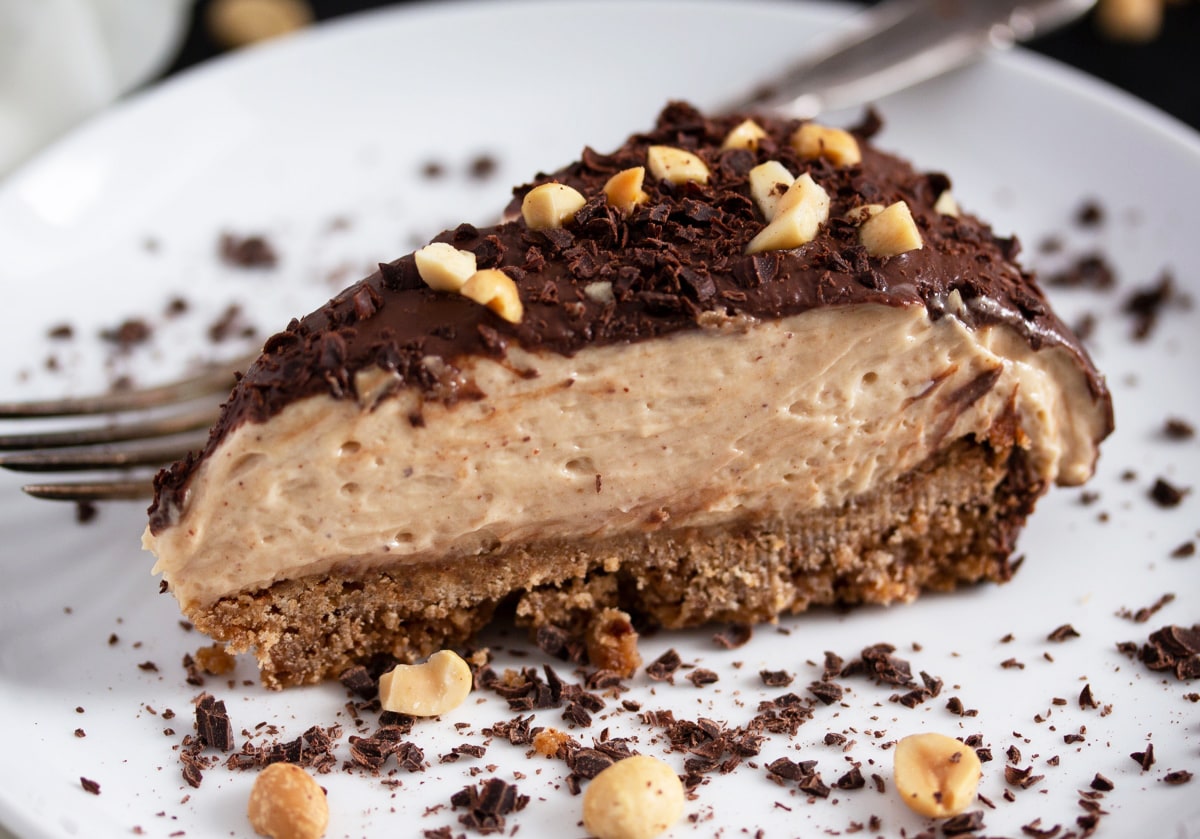 creamy slice of peanut butter pie with chocolate ganache and chopped peanuts.