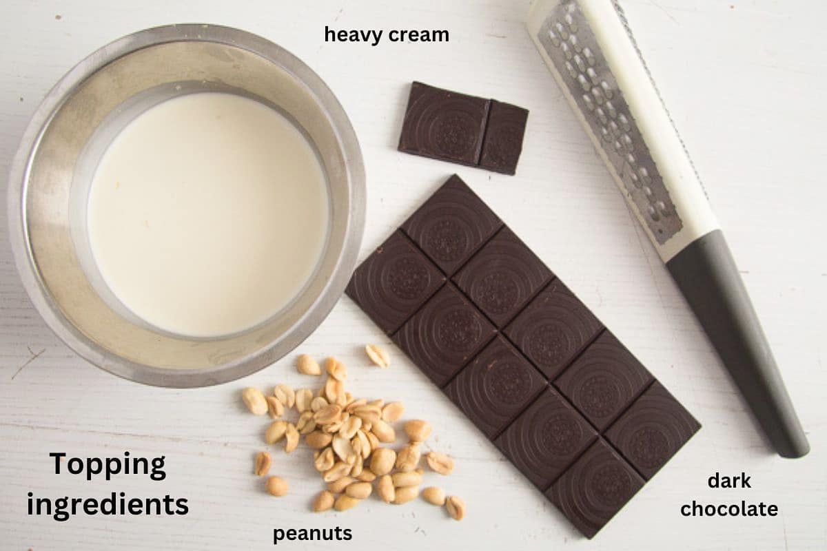 bowl of heavy cream, dark chocolate, peanuts and a small grater.
