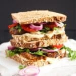 pork belly sandwich with mayonnaise, rocket, tomatoes and onions.