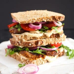 pork belly sandwich with mayonnaise, rocket, tomatoes and onions.