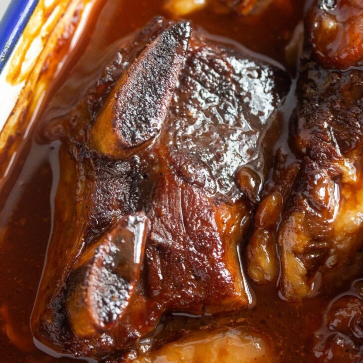 close up of baked beef ribs in the oven in bbq sauce.