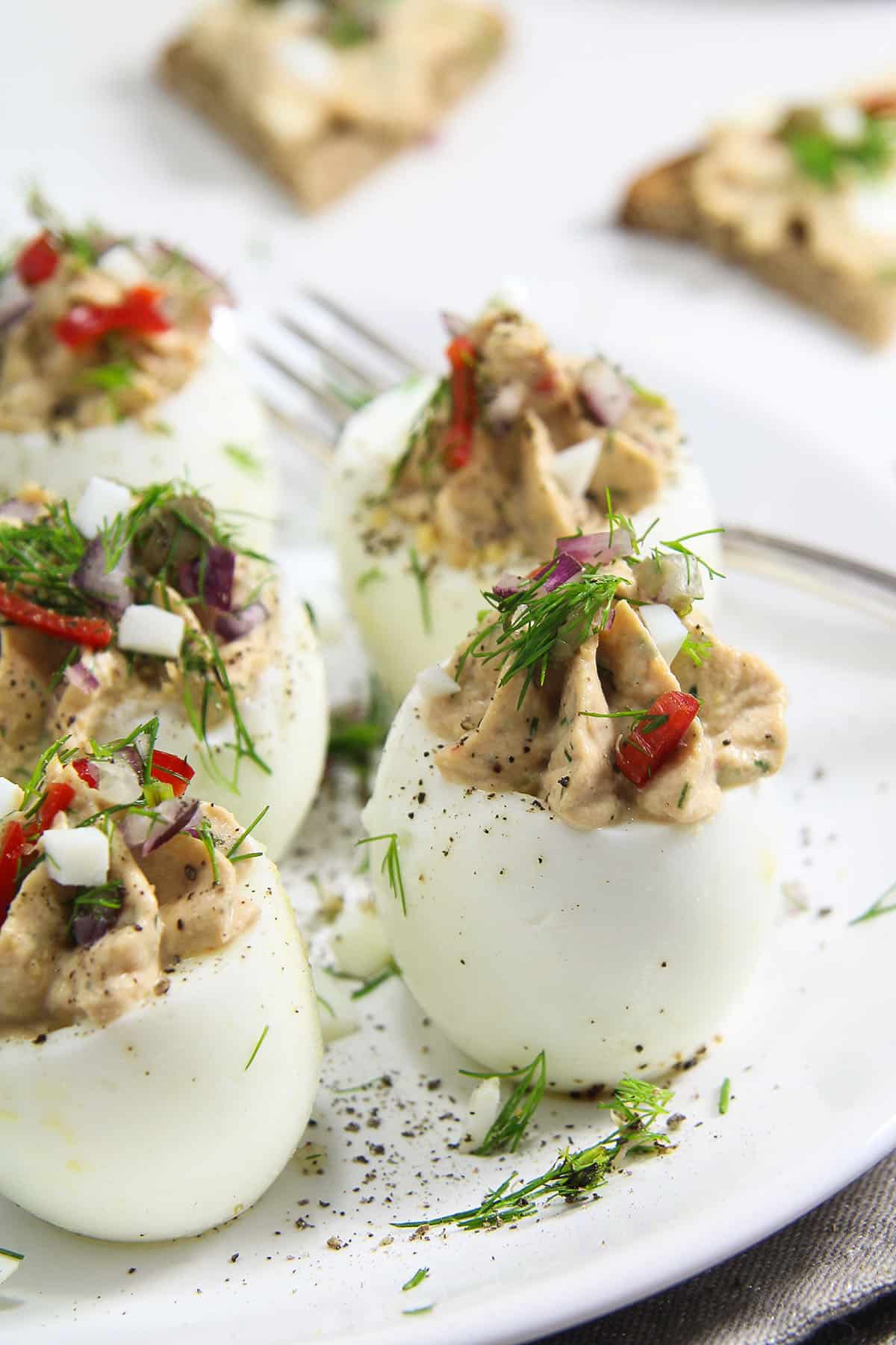 deviled eggs with tuna fish and capers on a plate.