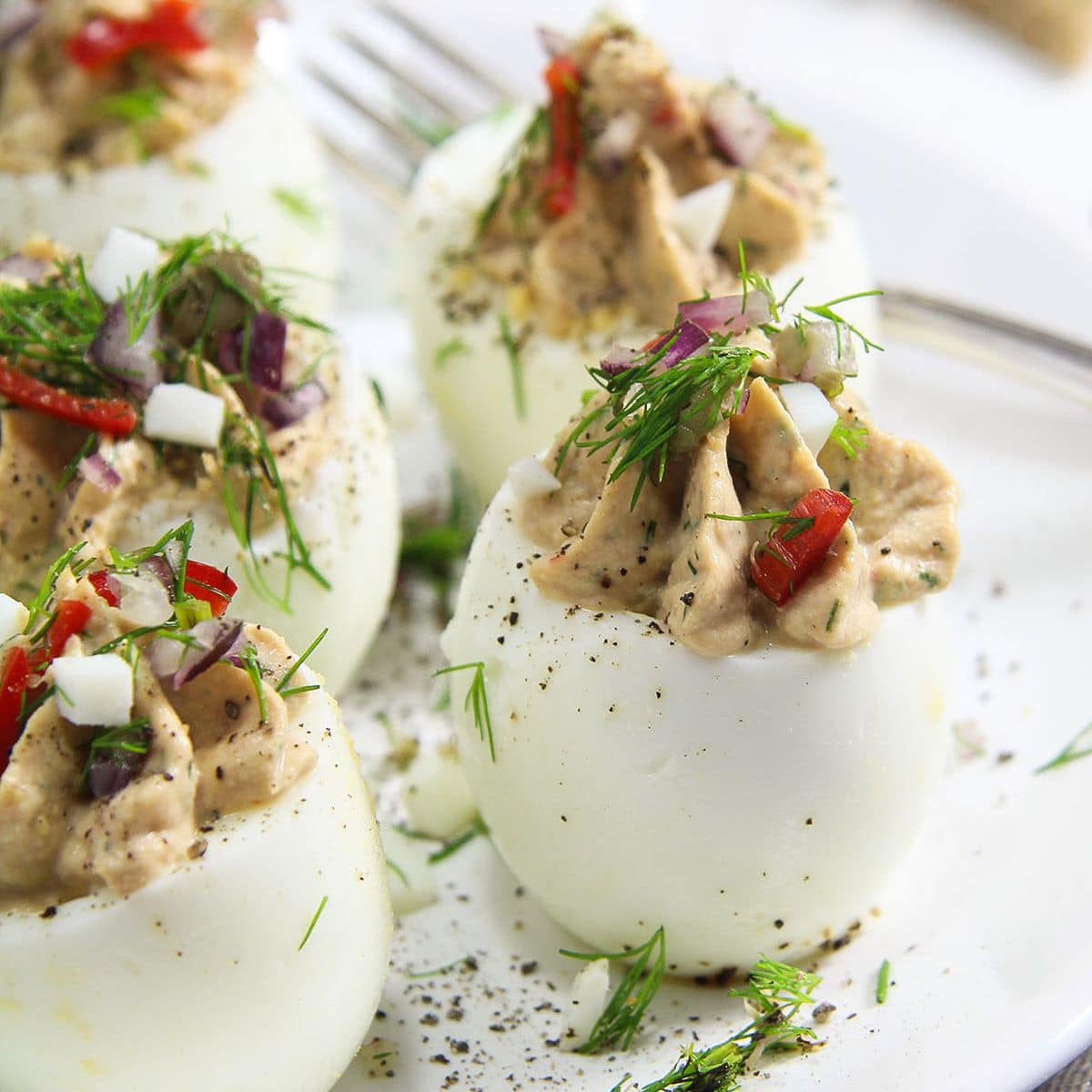 standing tuna fish deviled eggs garnished with dill on a plate.