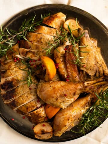 slow cooker turkey carved on a vintage platter with rosemary.