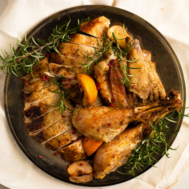 slow cooker turkey carved on a vintage platter with rosemary.