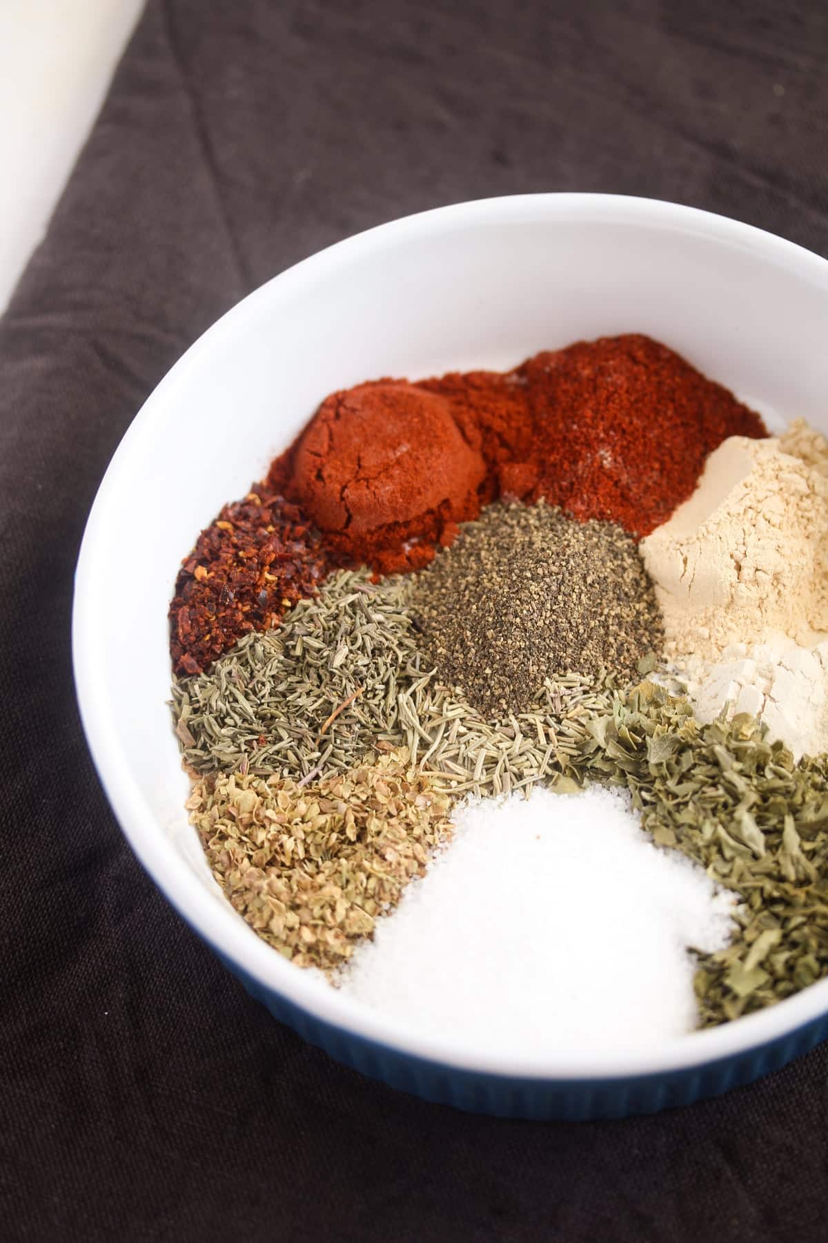 many spices for making homemade seasoning in a small white bowl.