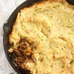 close up cast-iron skillet shepherd's pie sprinkled with parsley.
