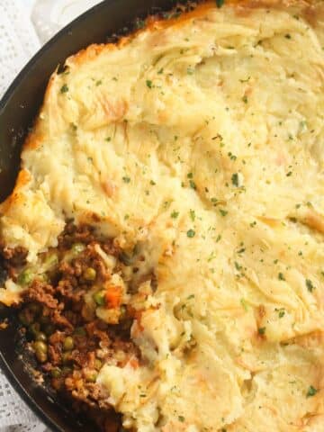 close up cast-iron skillet shepherd's pie sprinkled with parsley.