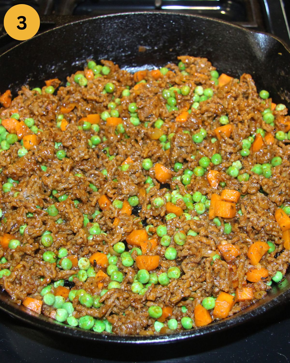 ground meat, carrots and peas cooking in a skillet.