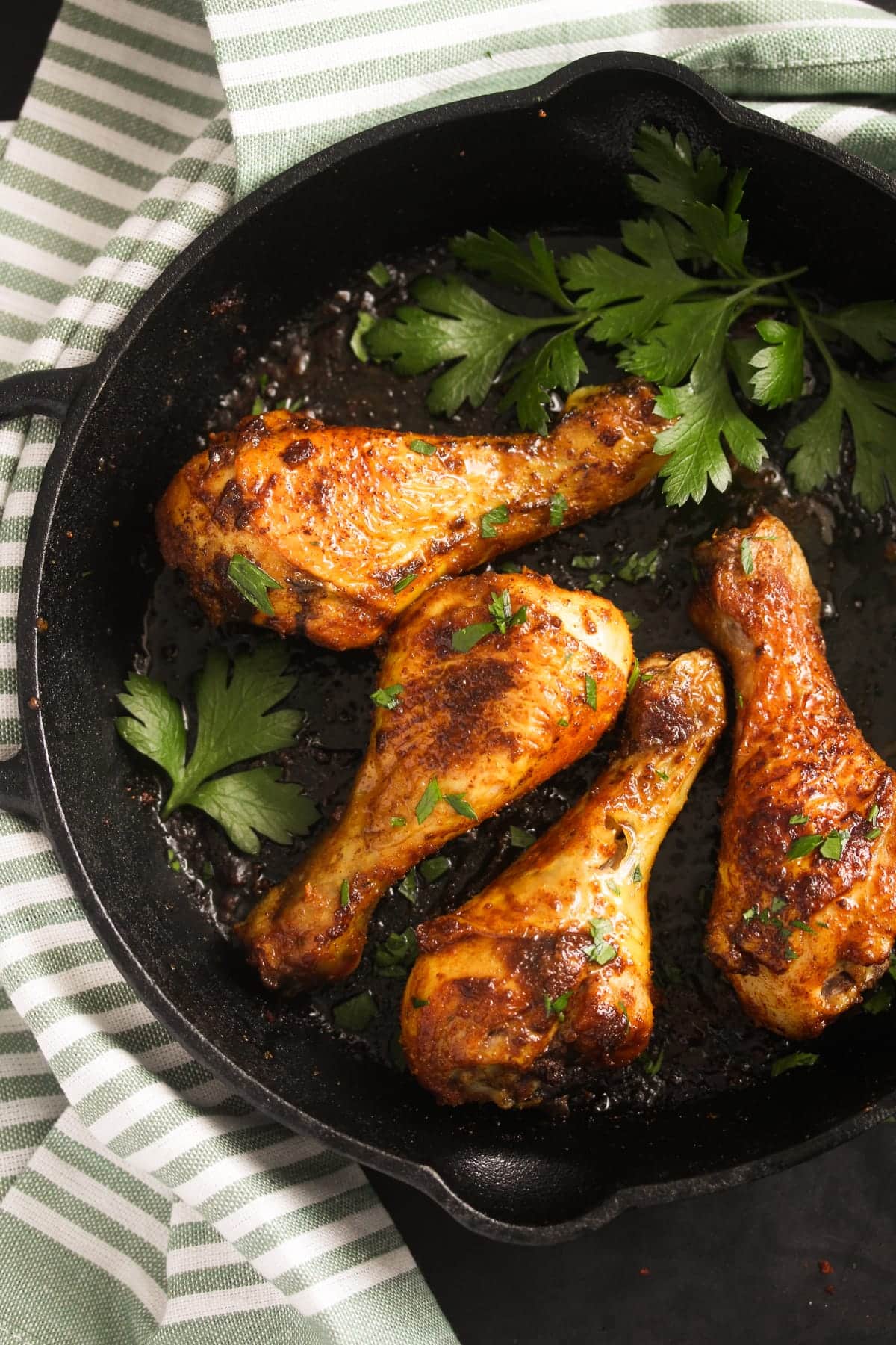 four large drumsticks in a cast iron skillet with parsley.