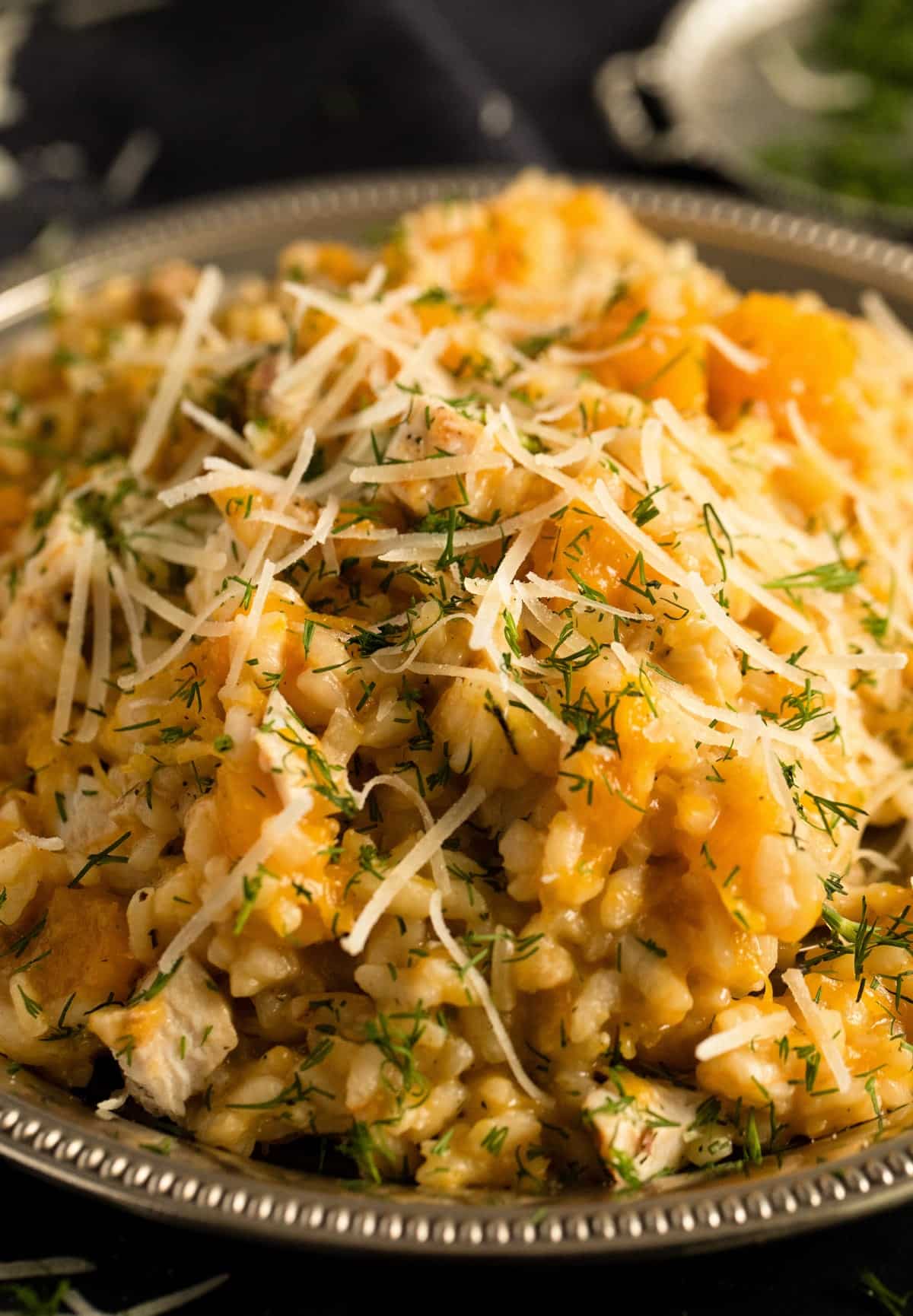 close up pumpkin risotto with chicken and parmesan piled on a plate.