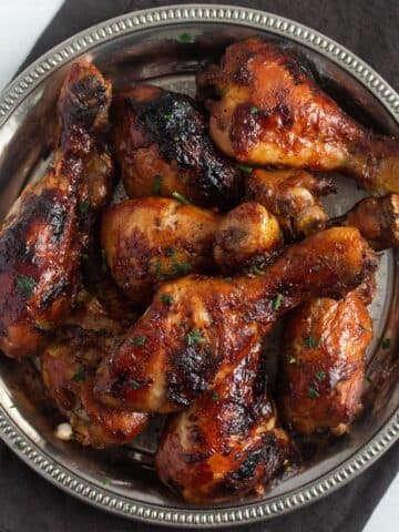 overhead view of a silver platter full of golden brown slow cooker chicken legs.