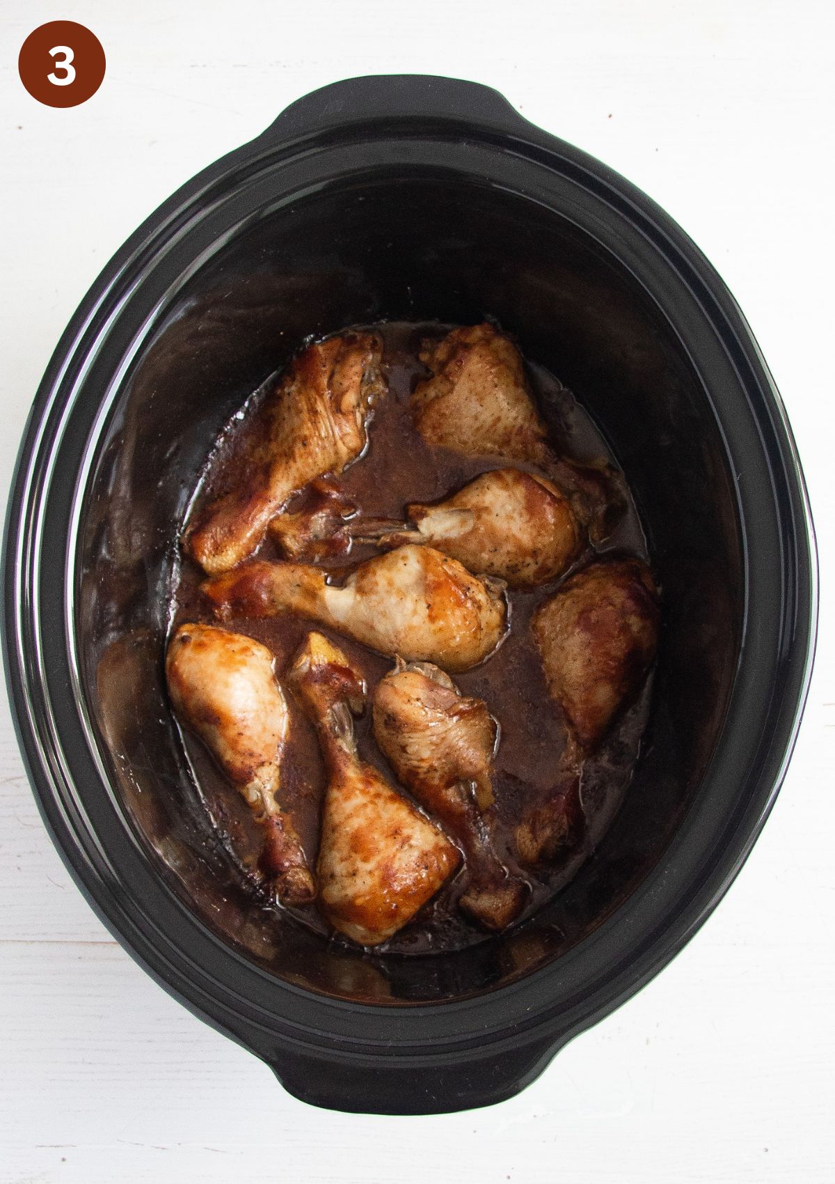 cooked chicken legs in the pot of a slow cooker.