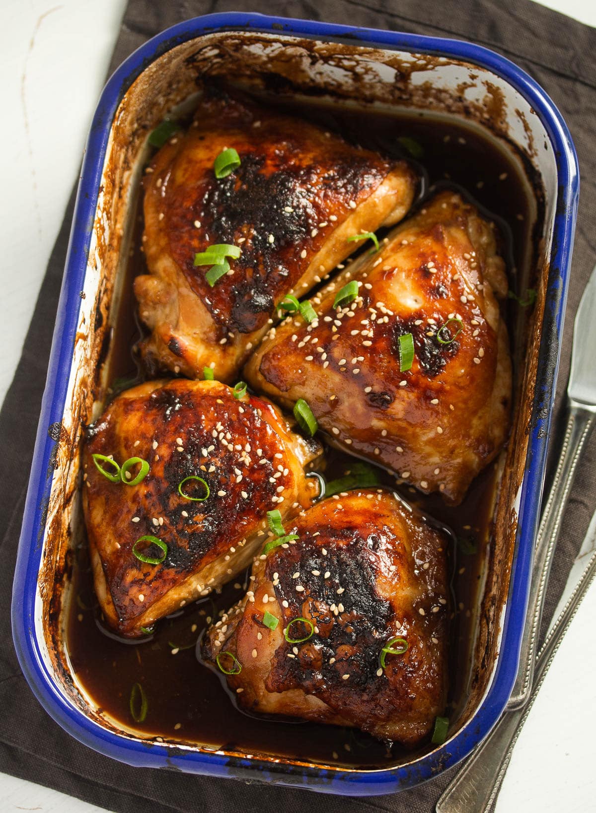four chicken thighs browned in a small baking dish.