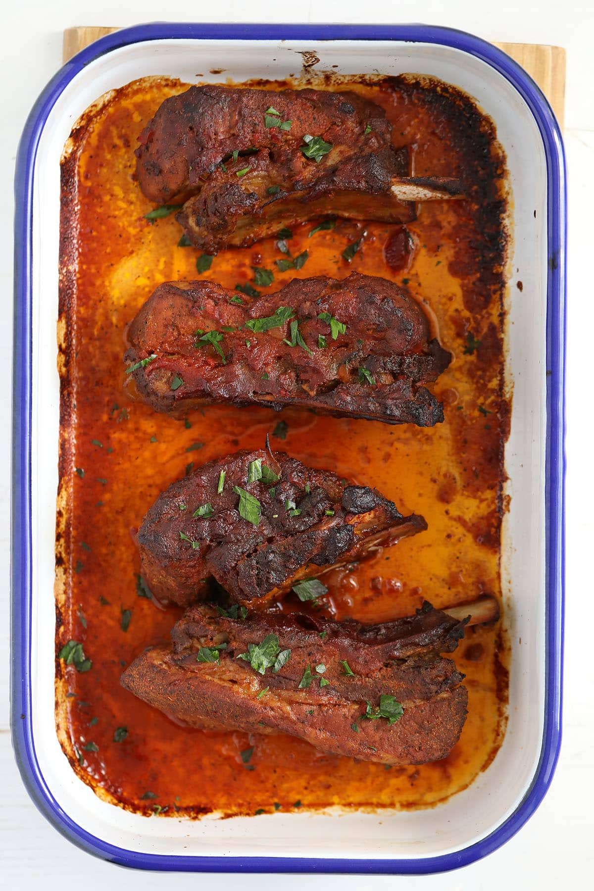 close up of pork ribs in orange-colored pan juices.